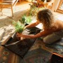 Fiskars Pflanzmatte faltbar im Einsatz: Frau pflanzt Zimmerpflanze auf der Matte. Praktischer Gartenhelfer.