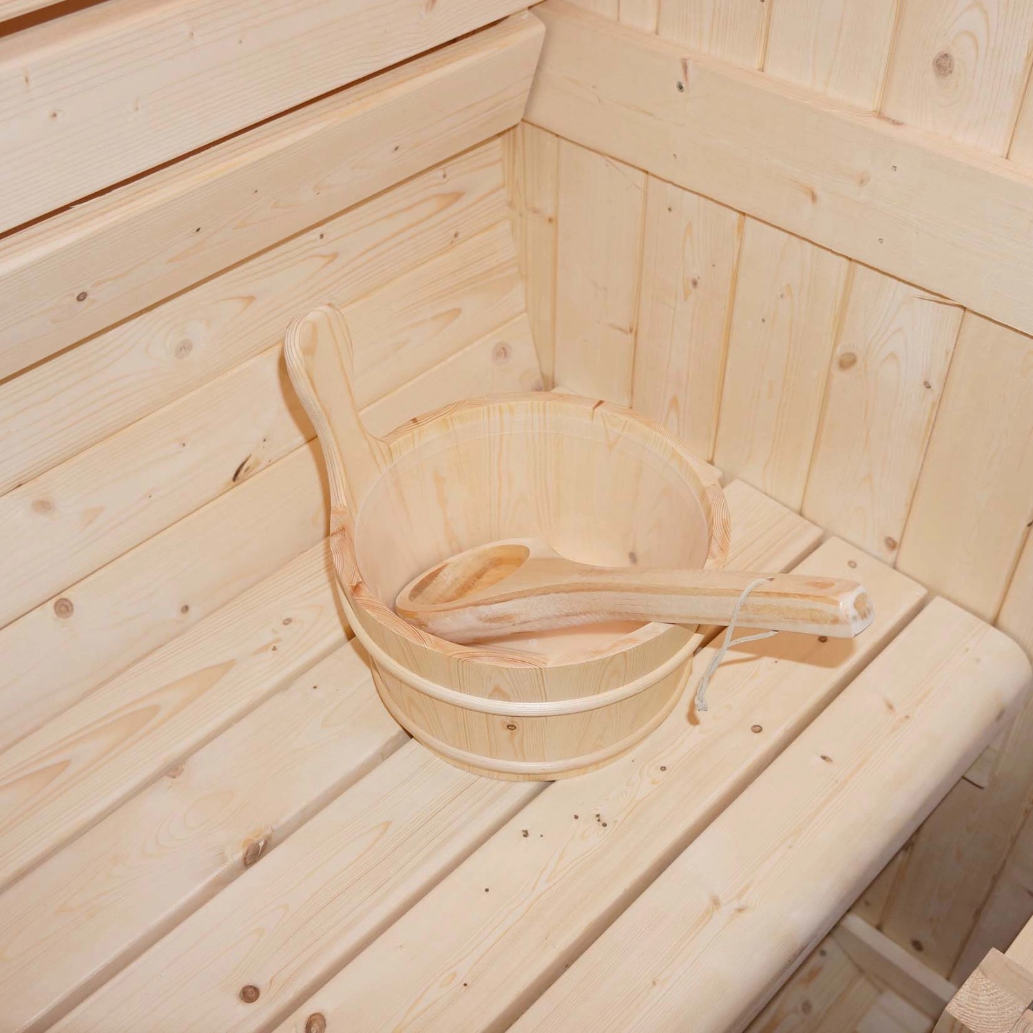 Fasssauna Lahti Deluxe: Saunakübel und Kelle aus Holz auf Saunabank im Innenraum.