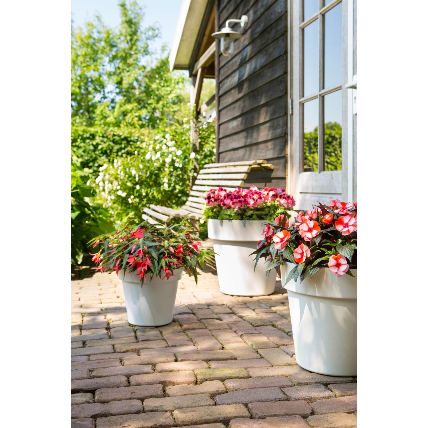 Florus Pflanztopf Paris Ø 30 in Olivgrün mit blühenden Pflanzen im Garten.