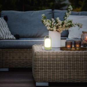 Brilo Akku-LED-Tischleuchte in Lindgrün auf einem Gartentisch. Dekorative Außenleuchte.