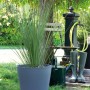 Grauer Deroma Untersetzer Origin Saucer 25 cm mit Pflanze im Garten.