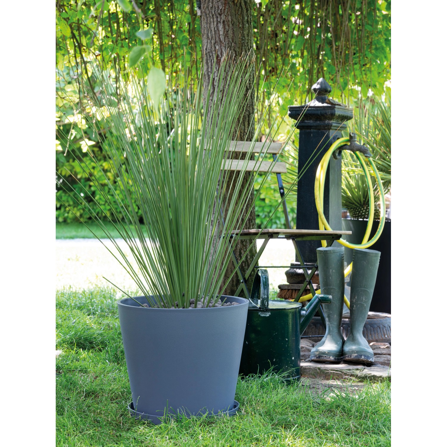 Grauer Deroma Untersetzer Origin Saucer 25 cm mit Pflanze im Garten.