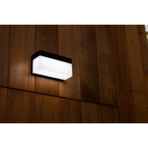 Schwarze Lutec LED Solar Wandleuchte Fran mit Bewegungsmelder an Holzwand.