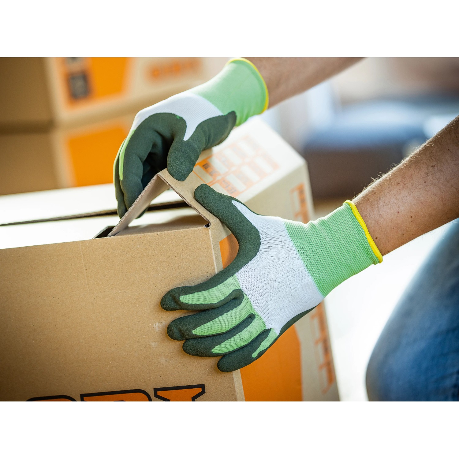 Hände mit LUX Arbeitshandschuhen Eco Gr. 9 beim Falten eines Kartons.