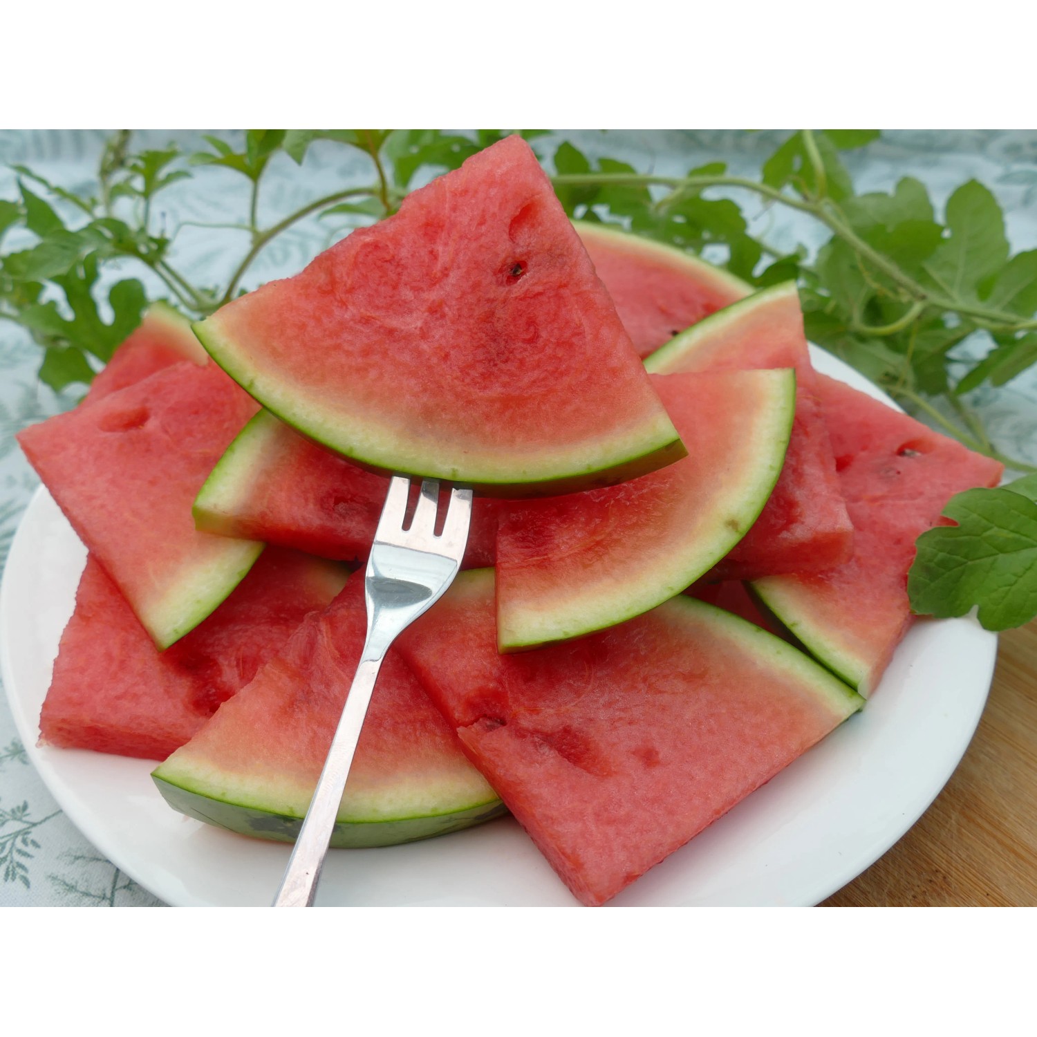 Teller mit angeschnittenen, saftigen Blu Bio Wassermelonenstücken mit Gabel.