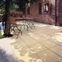 Verlegte Häusler Landhaus Steinplatten in Sandgelb auf einer Terrasse mit Gartenmöbeln.