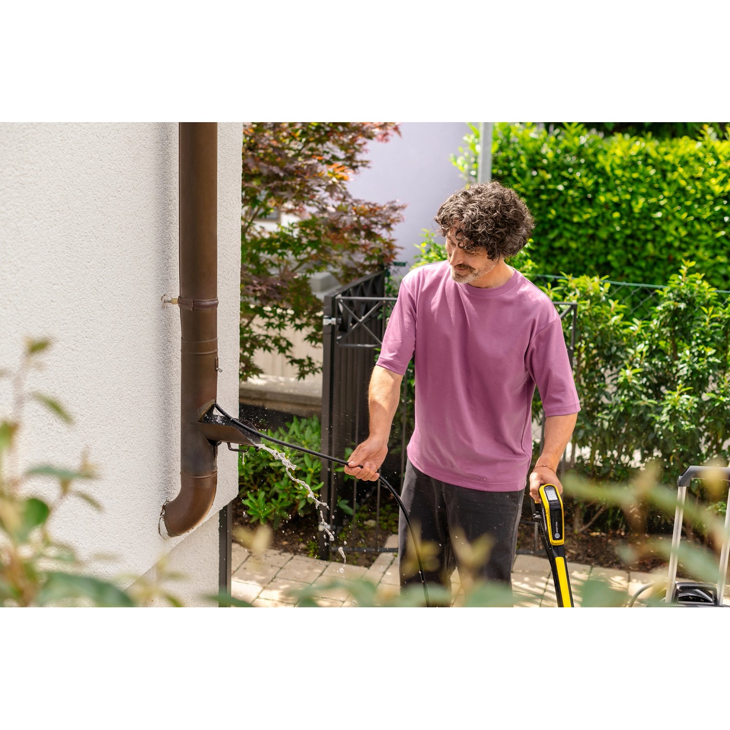 Mann reinigt Fallrohr mit Kärcher Rohrreinigungsset für Hochdruckreiniger.