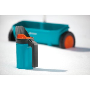 Gardena Kleinstreuer S in Türkis für Dünger und Streugut, mit Streuwagen im Hintergrund.