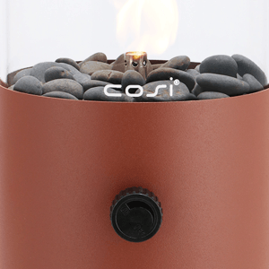 Cosi Cosiscoop Tisch-Gaslaterne Terra Brown mit brennender Flamme, Kieselsteinen und Glaszylinder. Regler sichtbar.