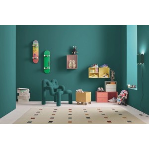 Wände in Alpina Pantone Deep Lake Cyan Innenfarbe in einem Jugendzimmer mit Skateboards, farbigen Möbeln und Teppich.