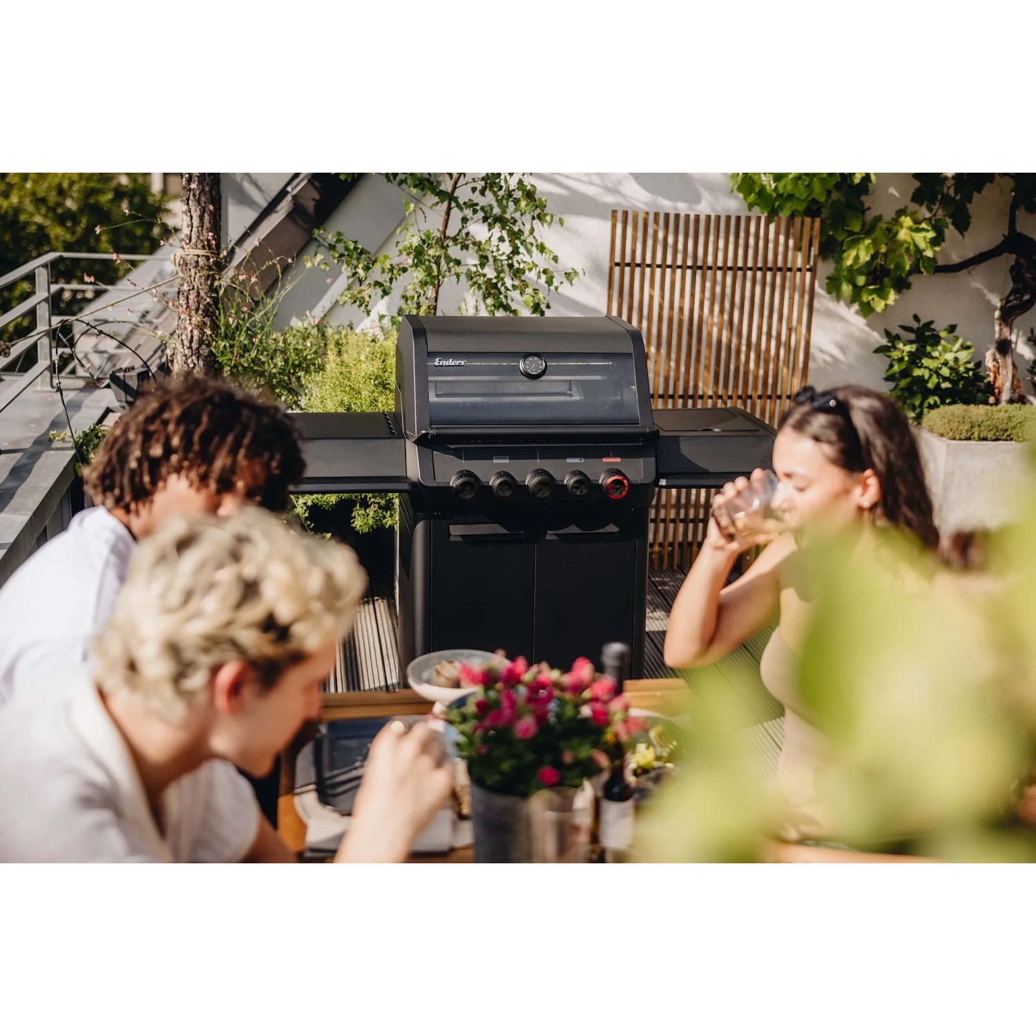 Enders Gasgrill Monroe Pro 3 SIKR Turbo Shadow in Schwarz mit Personen im Garten.
