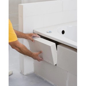 Handwerker verbaut Ytong Planstein PP2-0,50 an einer Badewanne. Porenbetonstein für den Innenausbau.