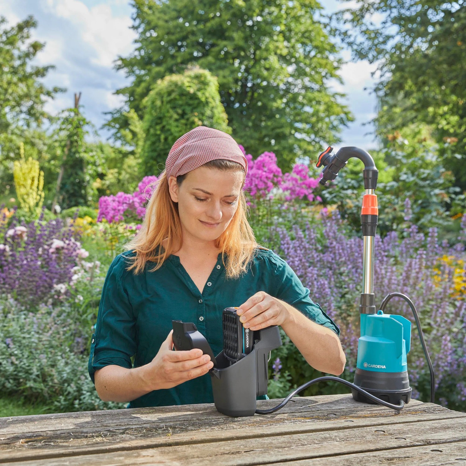 Frau montiert Gardena Akku-Regenfasspumpe 2000/2 18V. Gartenpumpe zur Regenwassernutzung.