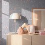 A.S. Creation Vliestapete mit Blumenmuster in Grau-Rosa an einer Wand, dekoriert mit Lampe und Vasen.
