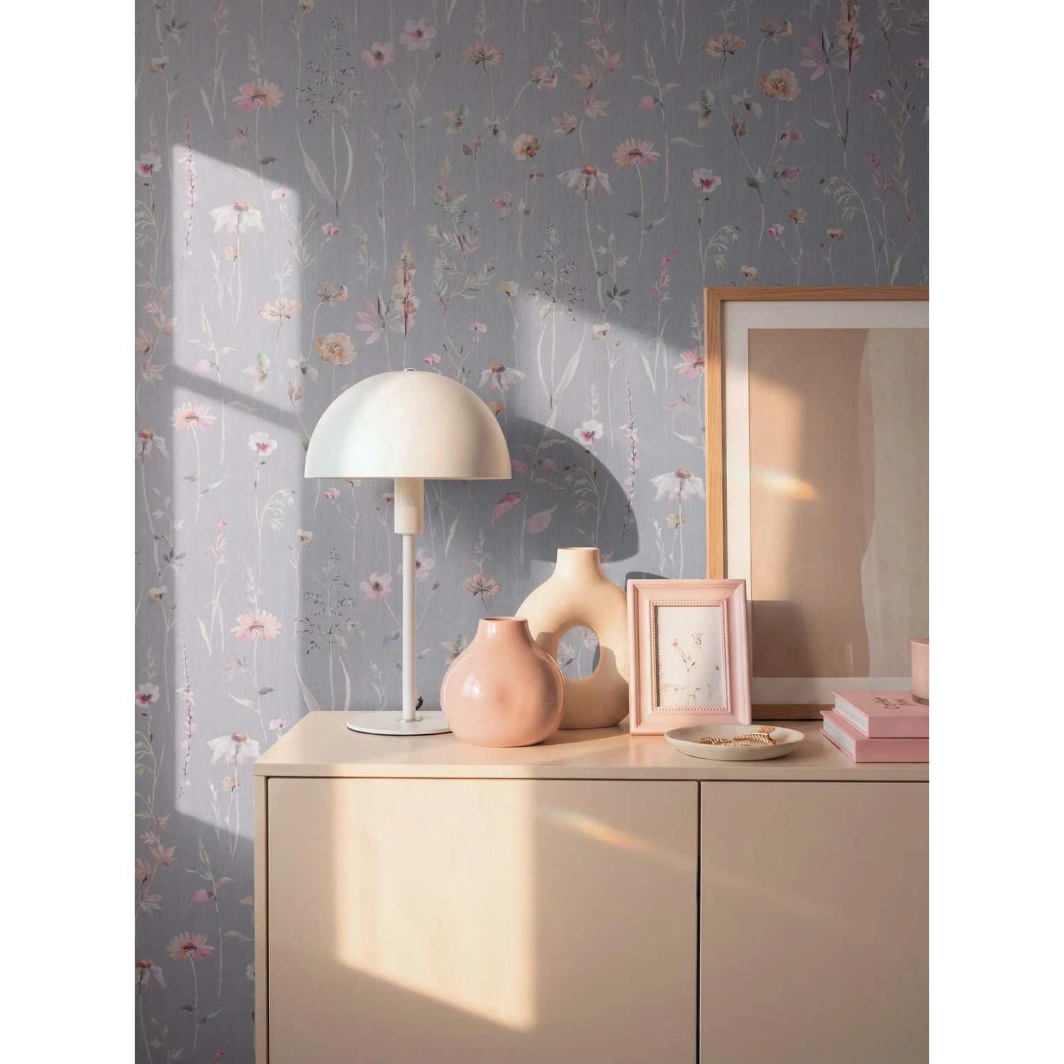 A.S. Creation Vliestapete mit Blumenmuster in Grau-Rosa an einer Wand, dekoriert mit Lampe und Vasen.