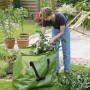 Grüner Gartenabfallsack (245 l) mit Frau beim Befüllen im Garten.