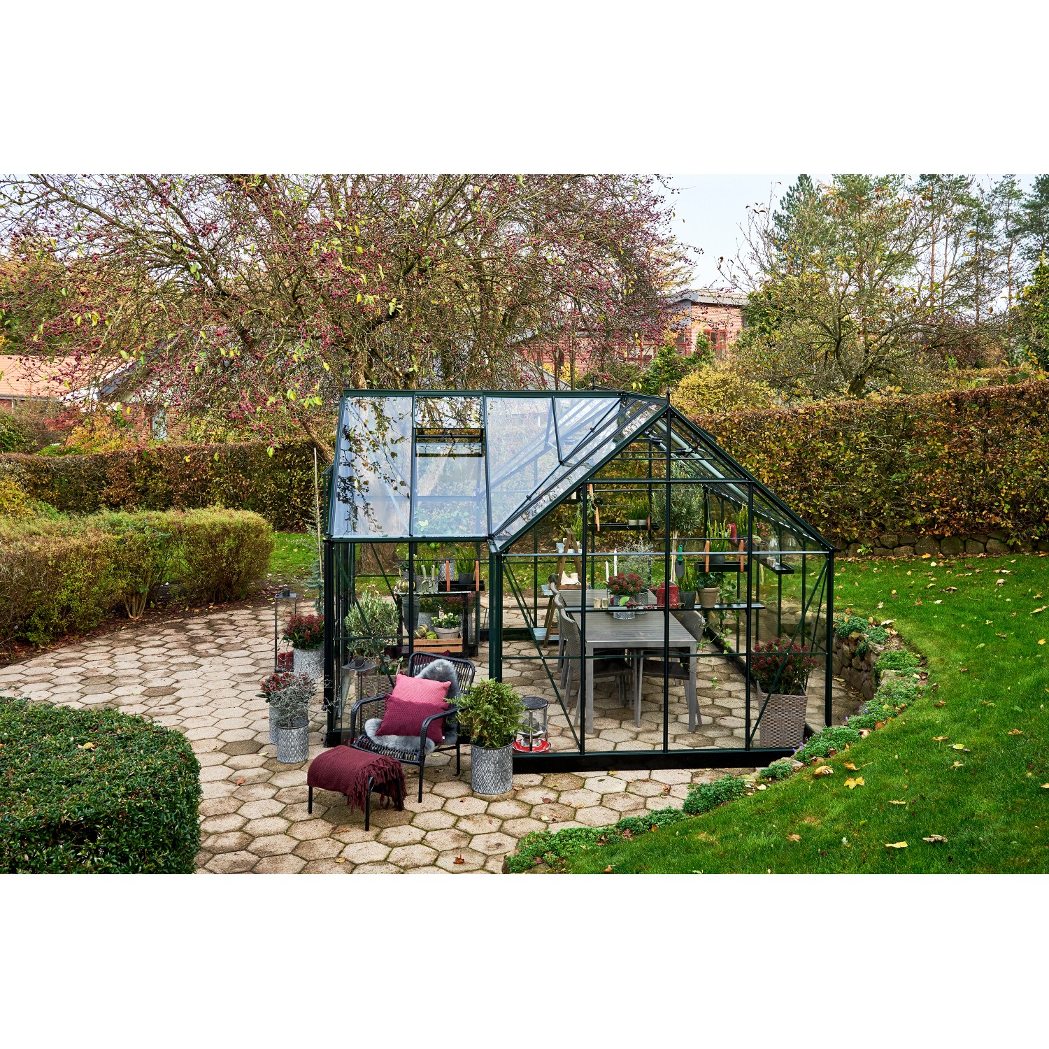 Halls Gewächshaus Garden Room, 12,9 m², grün, mit Sitzbereich und Pflanzen im Garten.