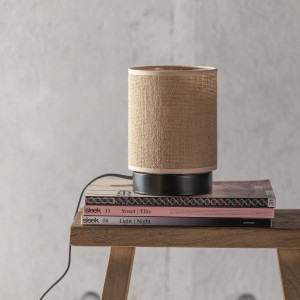 Brilliant Tischleuchte Aniela, schwarz/natur, auf Büchern auf einem Holztisch.