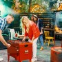 Roter Axi Kühlwagen mit Tischfußball, 65 l, auf einer Party mit mehreren Personen.