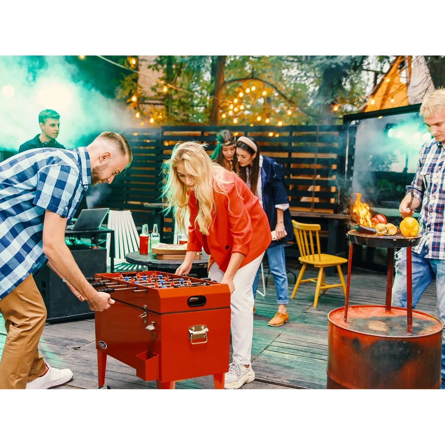 Roter Axi Kühlwagen mit Tischfußball, 65 l, auf einer Party mit mehreren Personen.