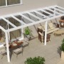 Weiße Terrassenüberdachung Professional (700x250cm) mit Glasdach und Sitzgruppe auf der Terrasse.