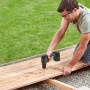 Mann schraubt mit Bosch 18V Akku-Schlagbohrschrauber Universalimpact 18V-60 Solo eine Holzterrasse.