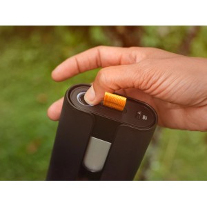 Hand drückt Knopf am schwarzen Fiskars 12V Akku für Akku-Gartenschere. Orange Lasche.