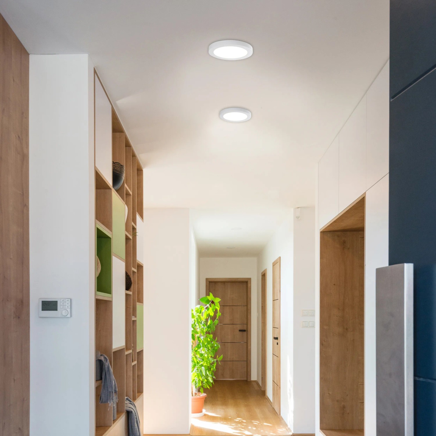 Zwei runde, weiße Näve LED-Deckenleuchten (24,7 cm) in einem hellen Flur.