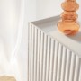 Weiße Selsey Fiorra Kommode mit geriffelten Fronten, abgesenkter Oberplatte und orangefarbener Vase. Modernes Sideboard.