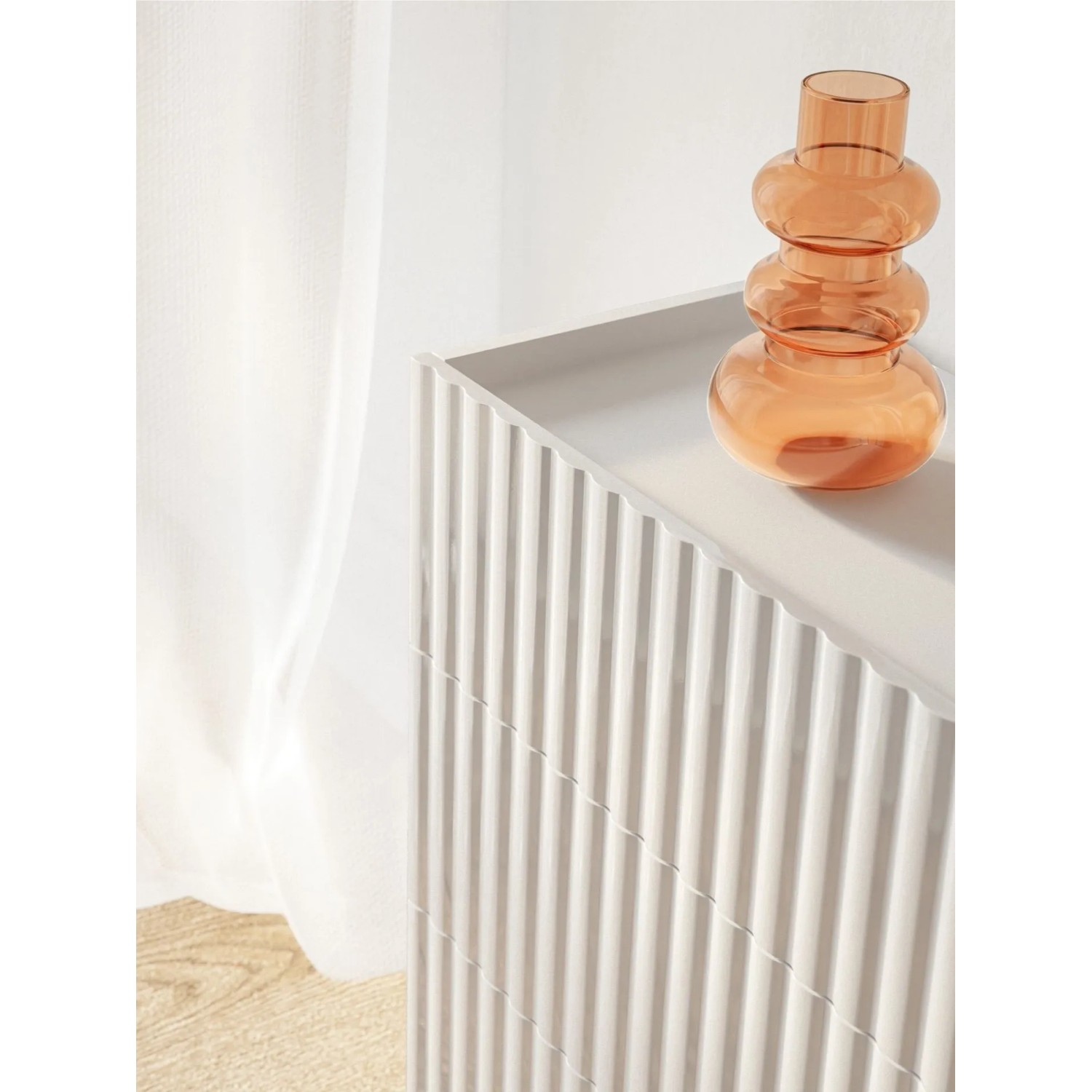 Weiße Selsey Fiorra Kommode mit geriffelten Fronten, abgesenkter Oberplatte und orangefarbener Vase. Modernes Sideboard.