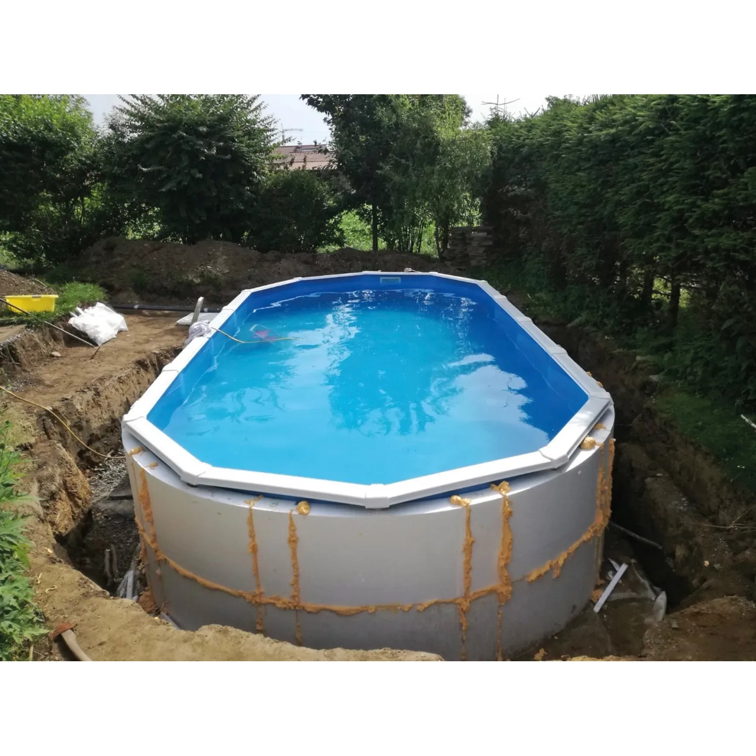 Ovaler Chemoform Stahlwandpool Protector T60 (940x485x60 cm) im Garten, teilweise im Boden eingelassen.