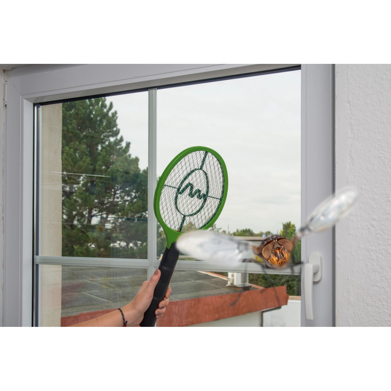 Grüne Gardigo Fliegenklatsche Bzzz beim Einsatz gegen eine Fliege vor einem Fenster.