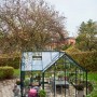 Halls Gewächshaus Garden Room, 12,9 m², grün, mit Sitzbereich im Garten.