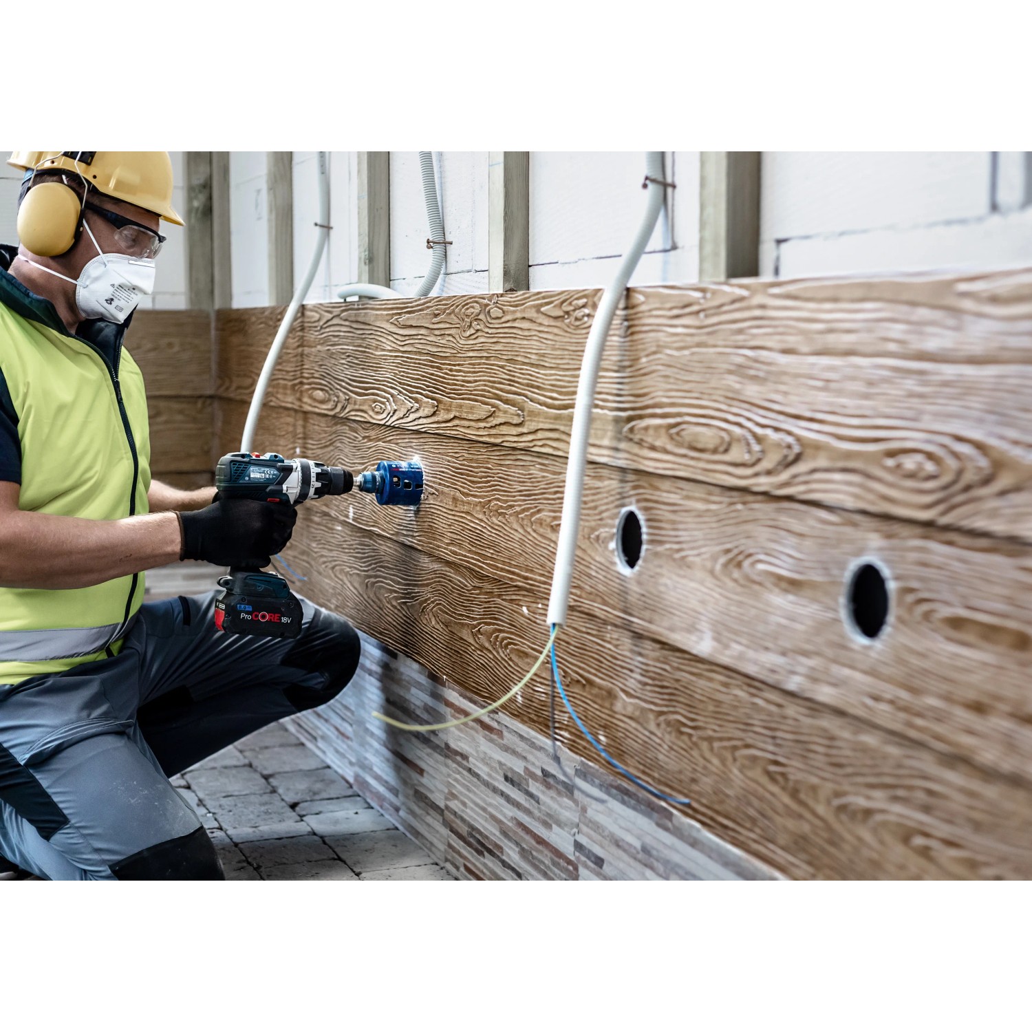 Handwerker bohrt Loch mit Bosch Expert Lochsäge Tough Material Ø 51 mm in Holzwand.