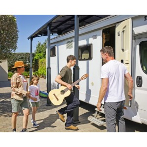 Anthrazitfarbener Canopia Carport mit gewölbtem Dach über Wohnmobil und Familie. Stabile Aluminium-Konstruktion.