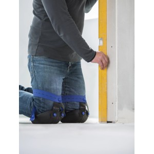 Mann mit LUX Knieschoner Classic für Fliesen beim Nivellieren an einer Wand.