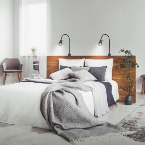 Schwarze Briloner LED Bettleuchten Tuso, schwenkbar, warmweißes Licht, montiert am Holzbett.