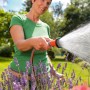 Frau bewässert Blumen mit Gardena Bewässerungsbrause. Gartenspritze mit Wasserstrahl.