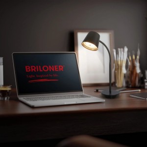 Schwarze Brilo Akku-Schreibtischlampe Biwo auf Schreibtisch mit Laptop.