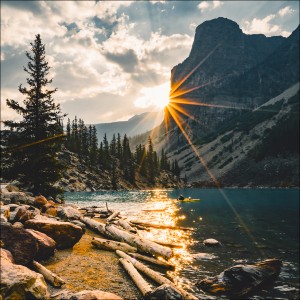 Pro Art Glasbild: Sonne am Bergsee (50x50 cm) mit Berg, See, Baum und Kanu im Sonnenlicht.