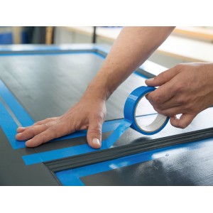 Anwendung von blauem LUX Malerband für Lacke auf einer grauen Oberfläche für präzise Farbkanten.