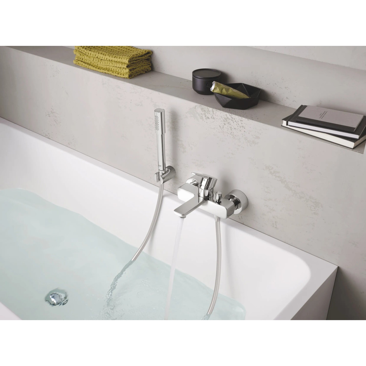 Grohe Lineare Wannenarmatur in Chrom mit Handbrause an gefüllter Badewanne.