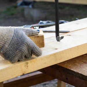 Schwarzes Brecheisen zieht Nagel aus Holzbrett. Vielseitiges Werkzeug-Set für Abbrucharbeiten und Hebeln.