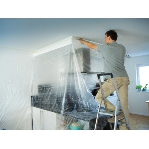 Mann deckt Küche mit LUX-TOOLS 2-in-1 Krepp und Folie ab. Transparente Abdeckfolie für Malerarbeiten & Renovierung.