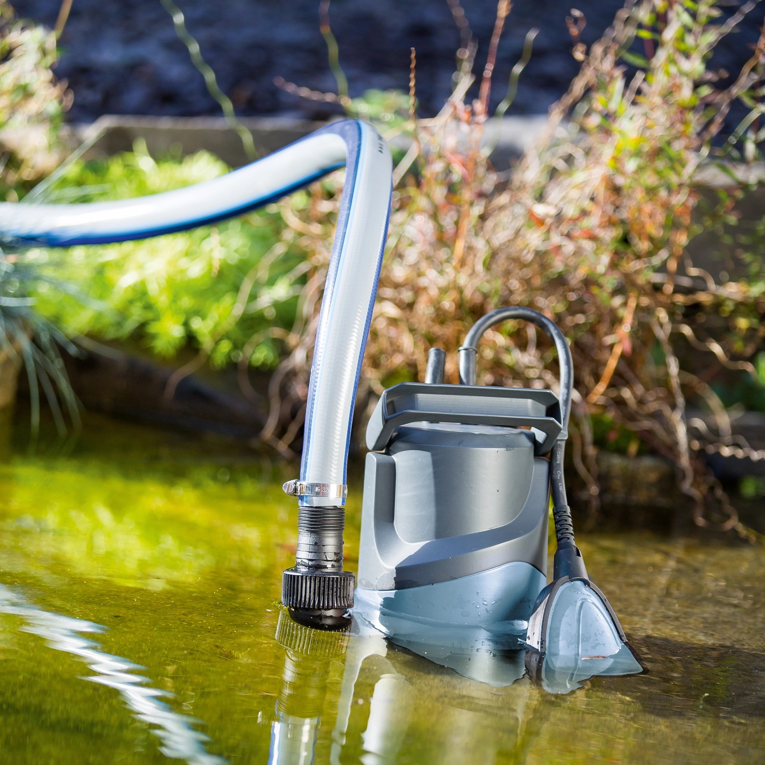 Schmutzwasserpumpe TPS 8000 (400 W) im Einsatz im Gartenteich mit angeschlossenem Schlauch.