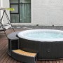 Mobiler, runder OBI Whirlpool im Rattan Design mit Treppe und sprudelndem Wasser.