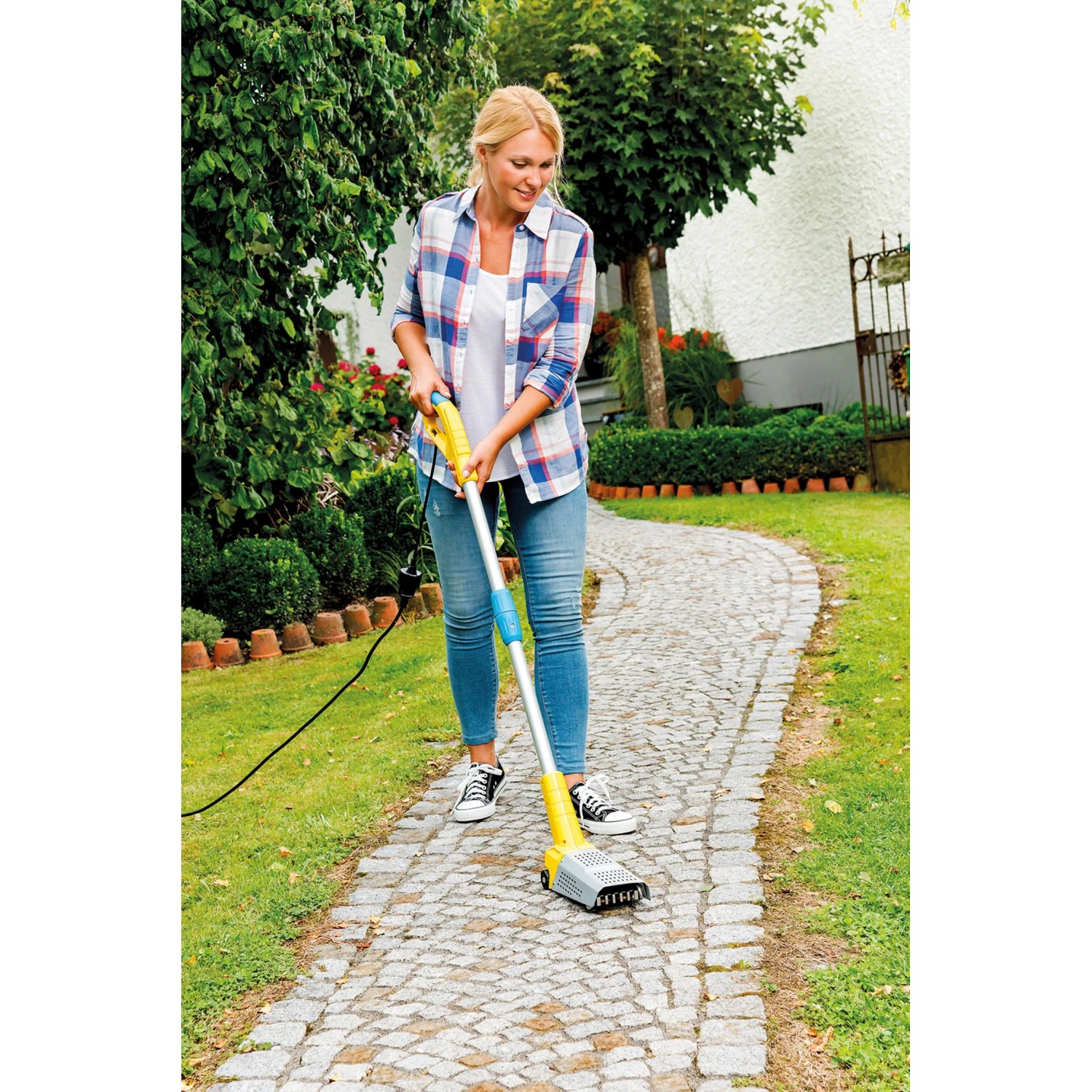 Frau nutzt Gloria Thermoflamm Bio Fix Unkrautbrenner auf Gehweg. Chemiefreie Unkrautentfernung.