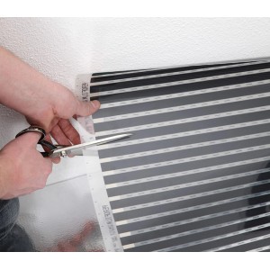 Zuschneiden der Heizfolie für Fußbodentemperierung mit einer Schere.