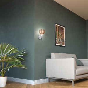 Wandleuchte Relax von Brilliant in Bronze und Chrom an grüner Wand im Wohnraum.