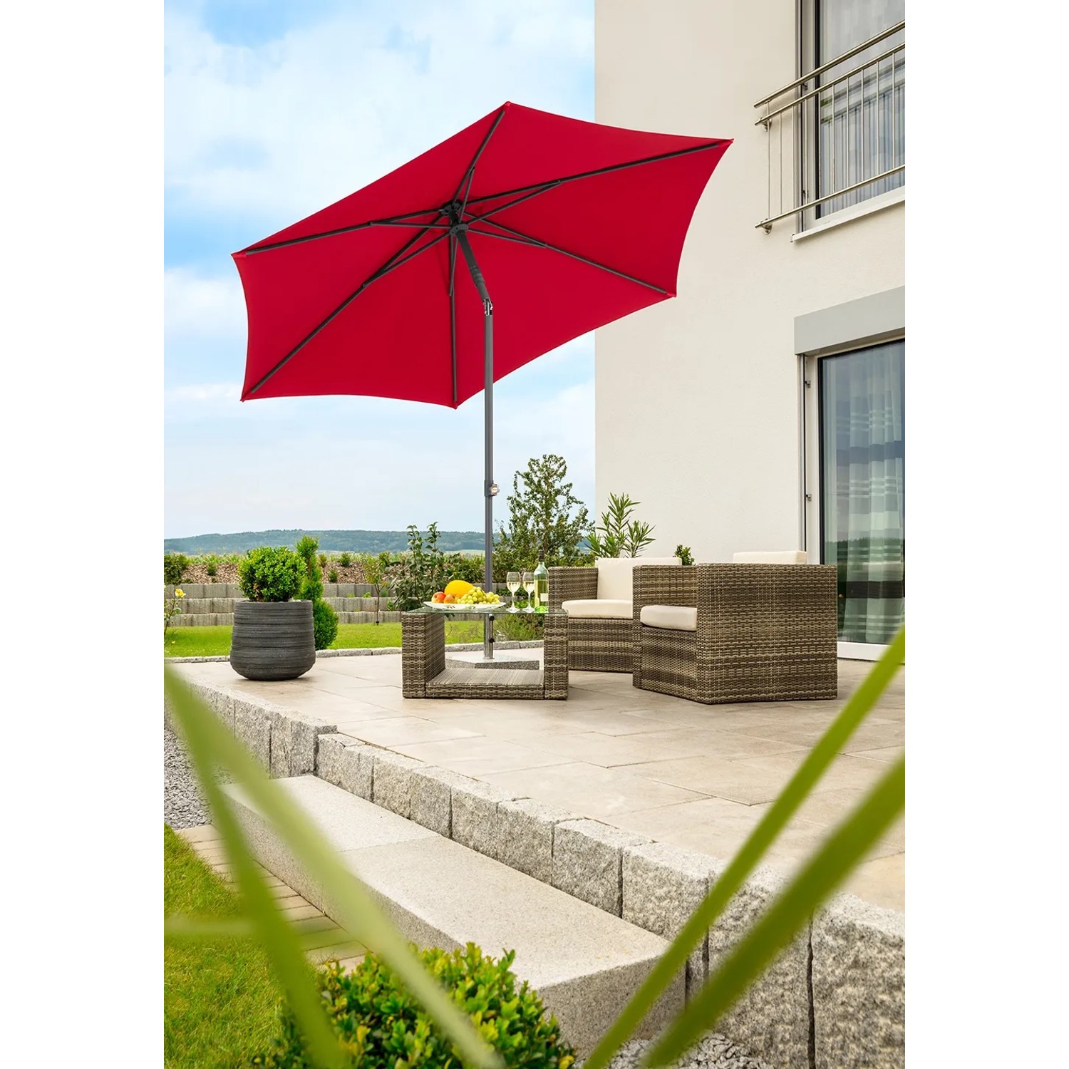 Roter Schneider Marktschirm mit Knickfunktion über einer Sitzecke im Garten.